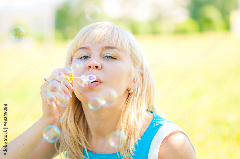 .Woman blowing bubbles in park .Woman blowing bubbles in park