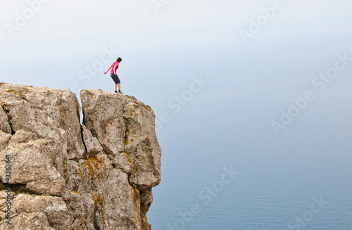 Lonely woman standing on the edge of the cliff