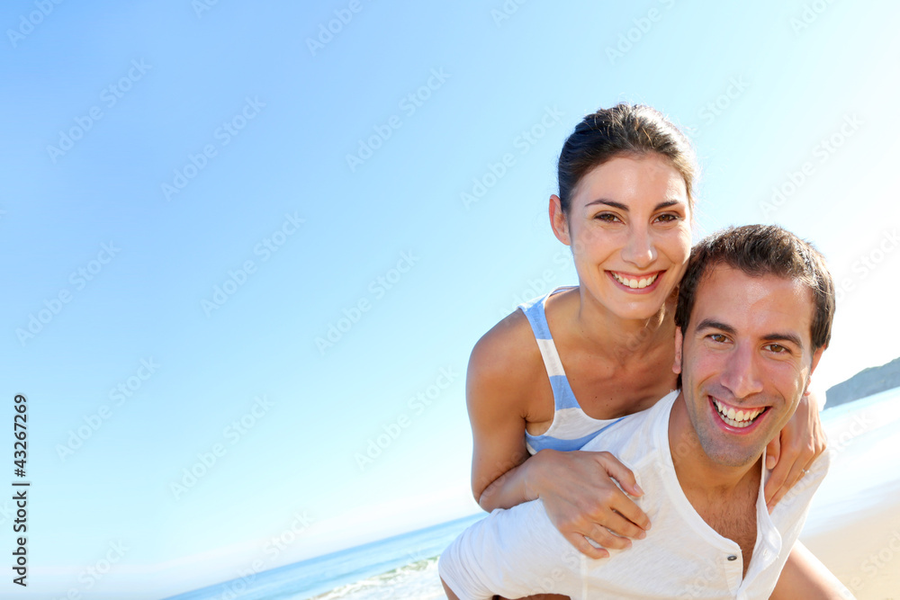 Man carrying girlfriend on his back at the beach Man carrying girlfriend on his back at the beach