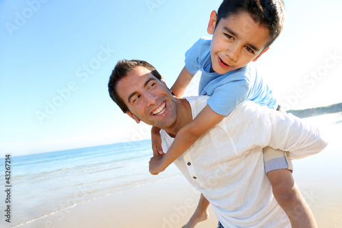 Father holding son on his shoulders at the beach