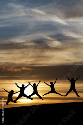 silhouette of teenagers jumping in sunset for fun