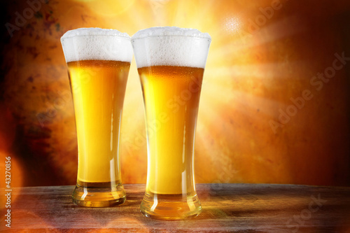 Beer into glass on golden background