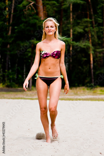 A young and beautiful woman walking along the sandy beach