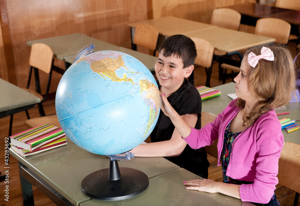 Schoolchildren exploring globe in classroom Schoolchildren exploring globe in classroom