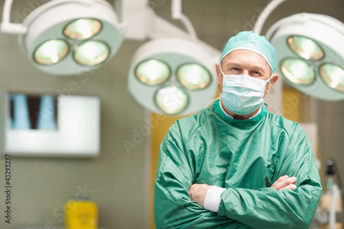 Smiling surgeon crossing his arms while standing photo