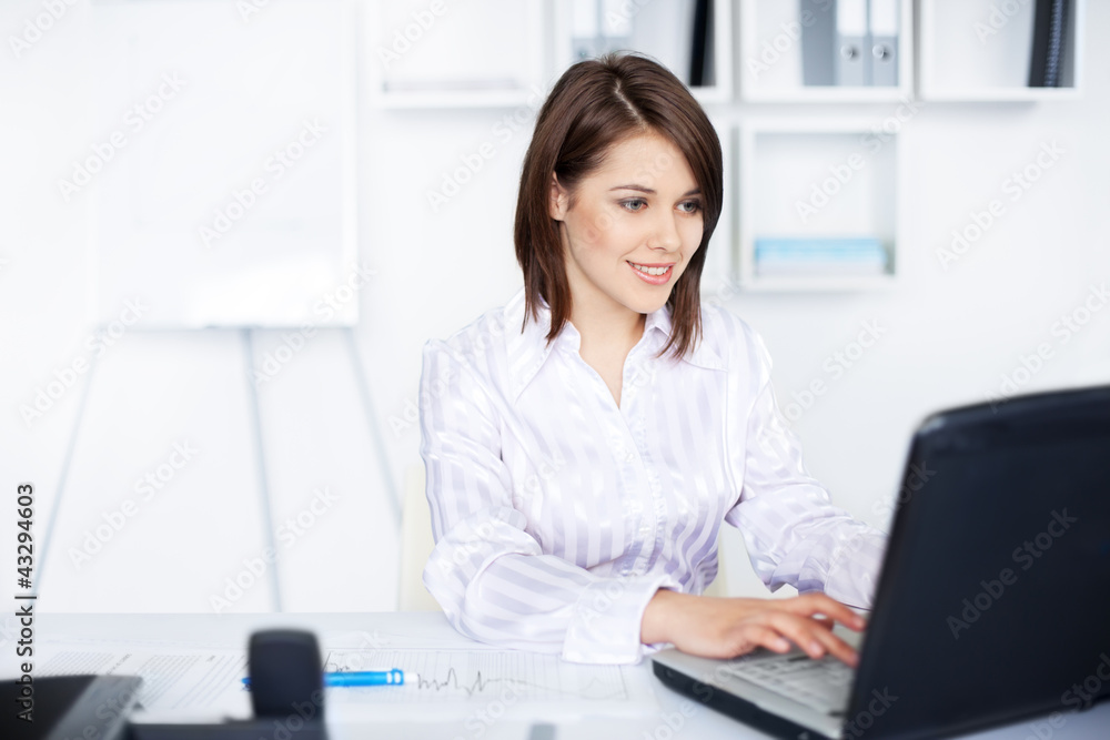 smiling business woman working on a laptop at office smiling business woman working on a laptop at office