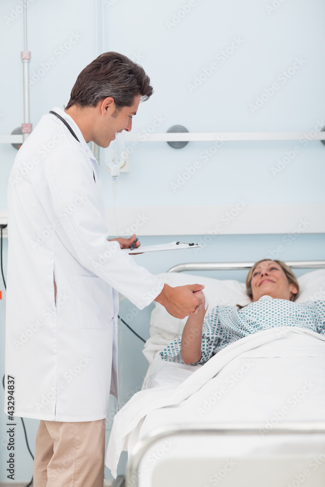 Obraz premium Doctor talking to his patient while holding her hand