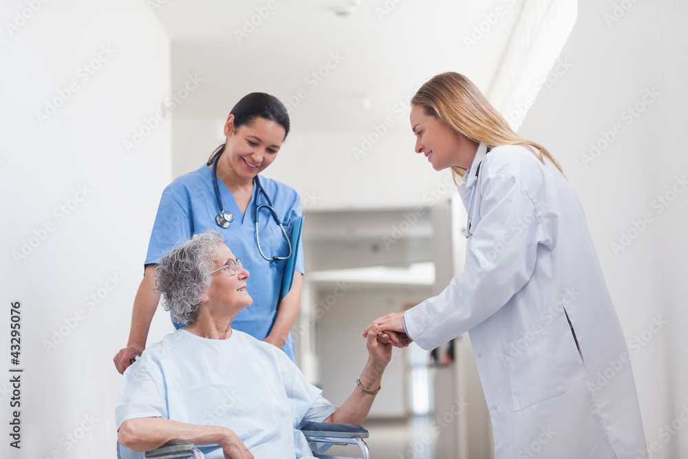 Patient in a wheelchair holding hand of a doctor Patient in a wheelchair holding hand of a doctor