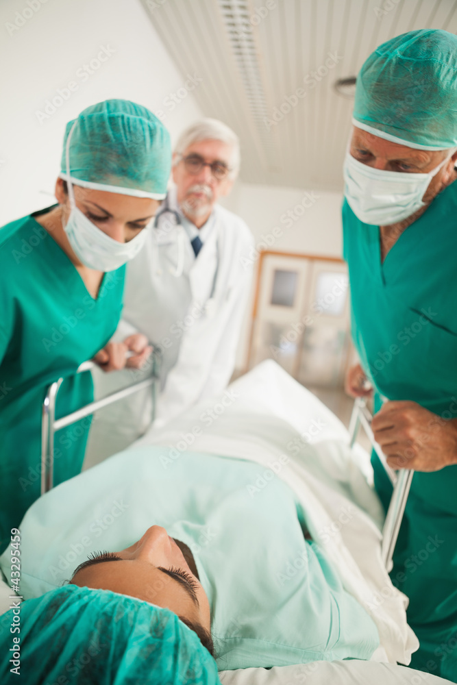 Patient lying on a medical bed next to doctors Patient lying on a medical bed next to doctors