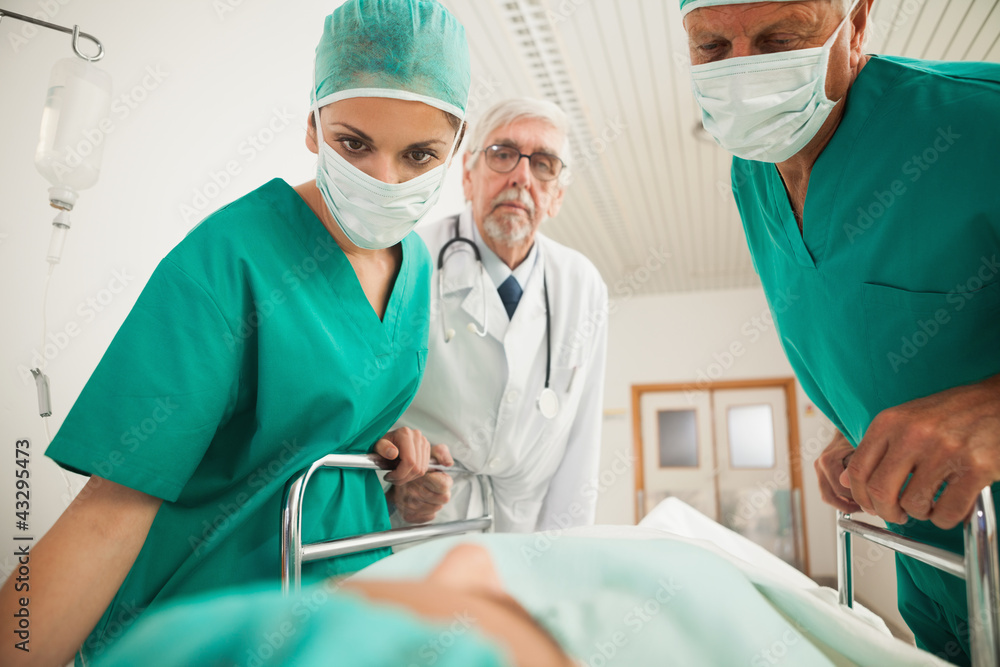 Doctors looking at a patient while leaning on a bed Doctors looking at a patient while leaning on a bed