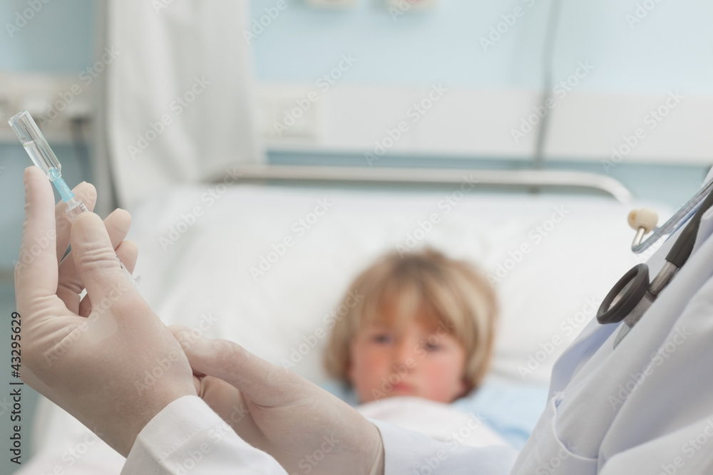 Doctor preparing a syringe in front of a child Doctor preparing a syringe in front of a child