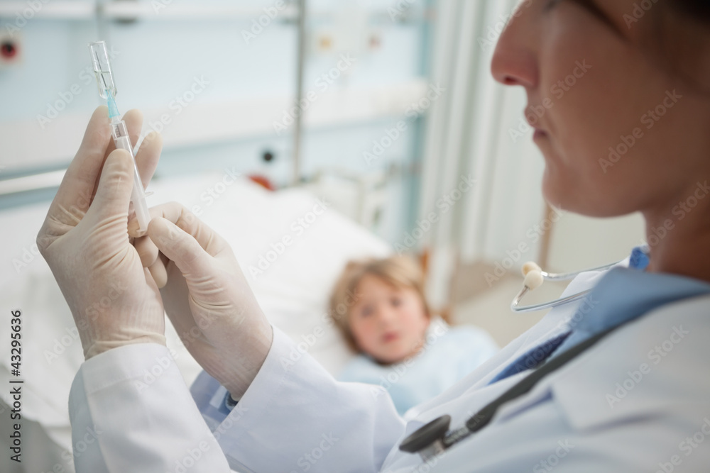 Obraz premium Doctor preparing a syringe next to a child