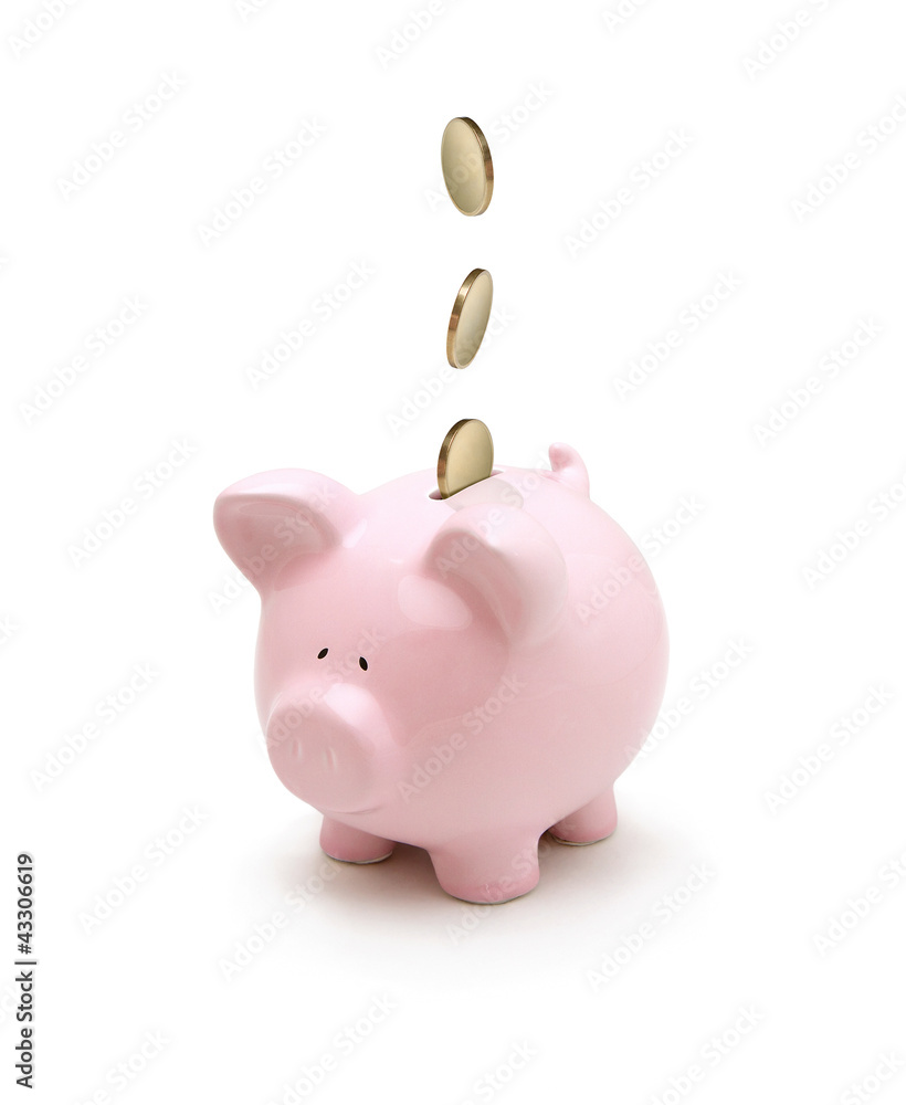 Obraz premium Golden coins falling into a piggy bank isolated on white