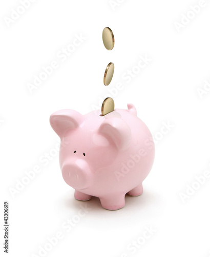 Fotografija Golden coins falling into a piggy bank isolated on white