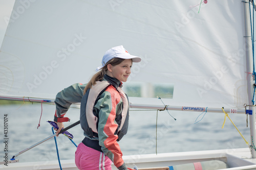 The girl operates the yacht the Optimist