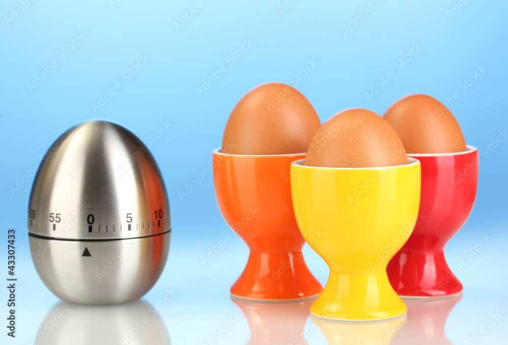 egg timer and egg in color stand on blue background egg timer and egg in color stand on blue background