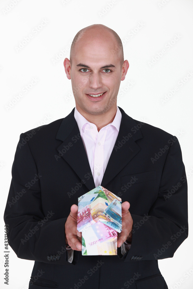 businessman holding a model of house made of money businessman holding a model of house made of money