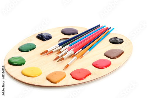 wooden art palette with paint and brushes.isolated on white