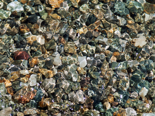 Crystal clear wave lapping over multi colored pebbles photo