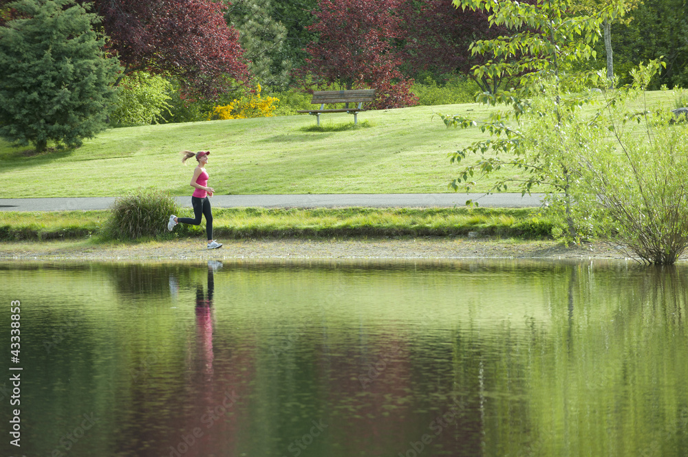 Jogger running near park pond Jogger running near park pond