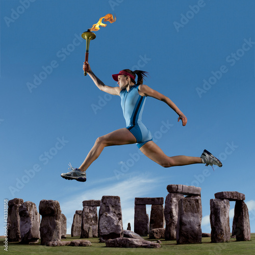 Athlete running with Olympic torch near Stonehenge photo