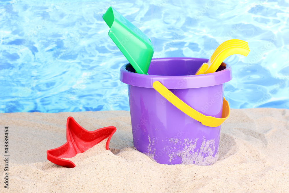 Children's beach toys on sand on water background Children's beach toys on sand on water background