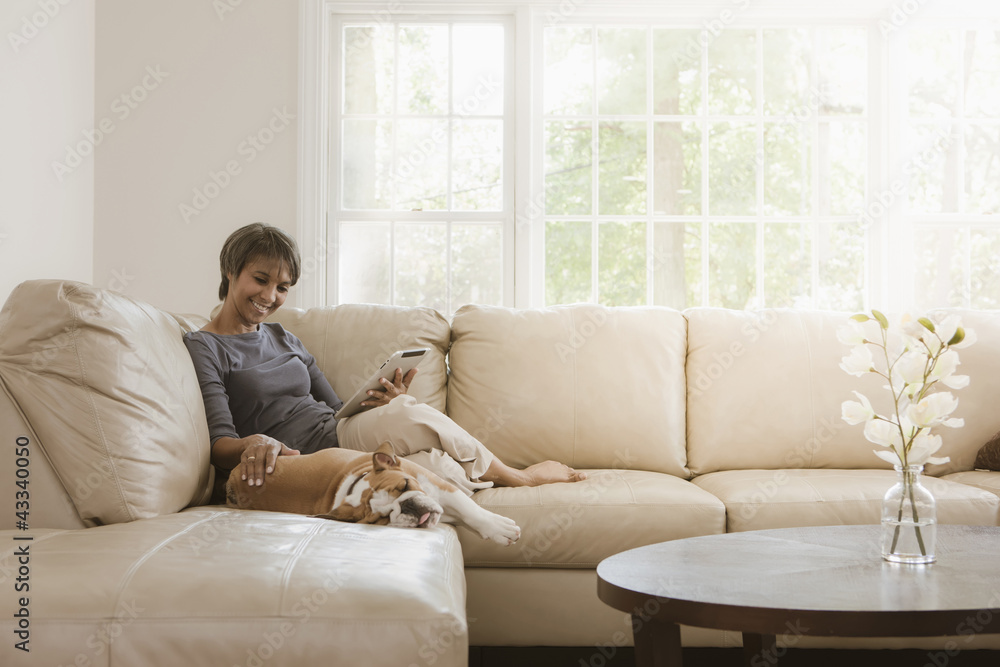Native American woman relaxing on sofa with English bulldog Native American woman relaxing on sofa with English bulldog