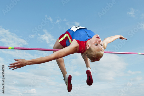 Caucasian athlete jumping over bar photo