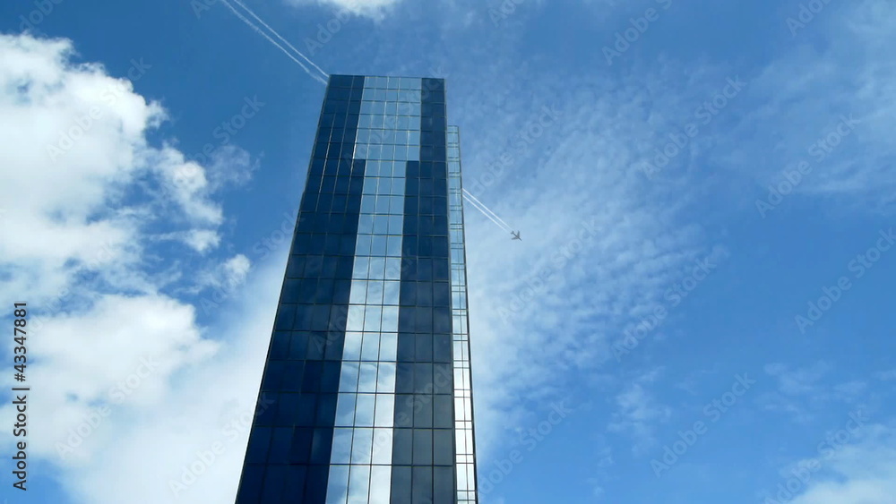 A skyscraper withmoving clouds and a jet leaving a contrail. A skyscraper withmoving clouds and a jet leaving a contrail.