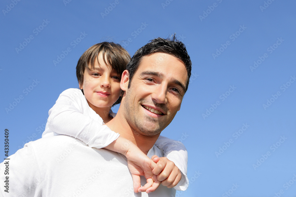 Boy riding piggy back on his father's back Boy riding piggy back on his father's back