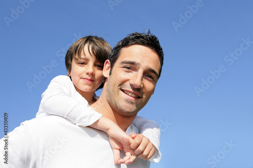 Foto Boy riding piggy back on his father's back