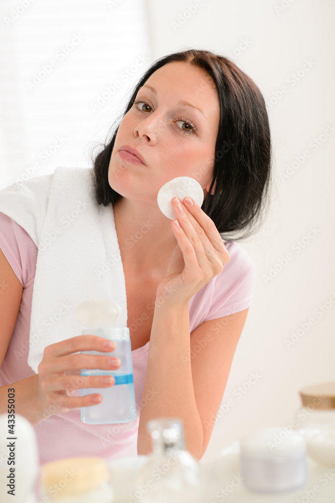 Woman cleaning face with cotton pad bathroom Woman cleaning face with cotton pad bathroom
