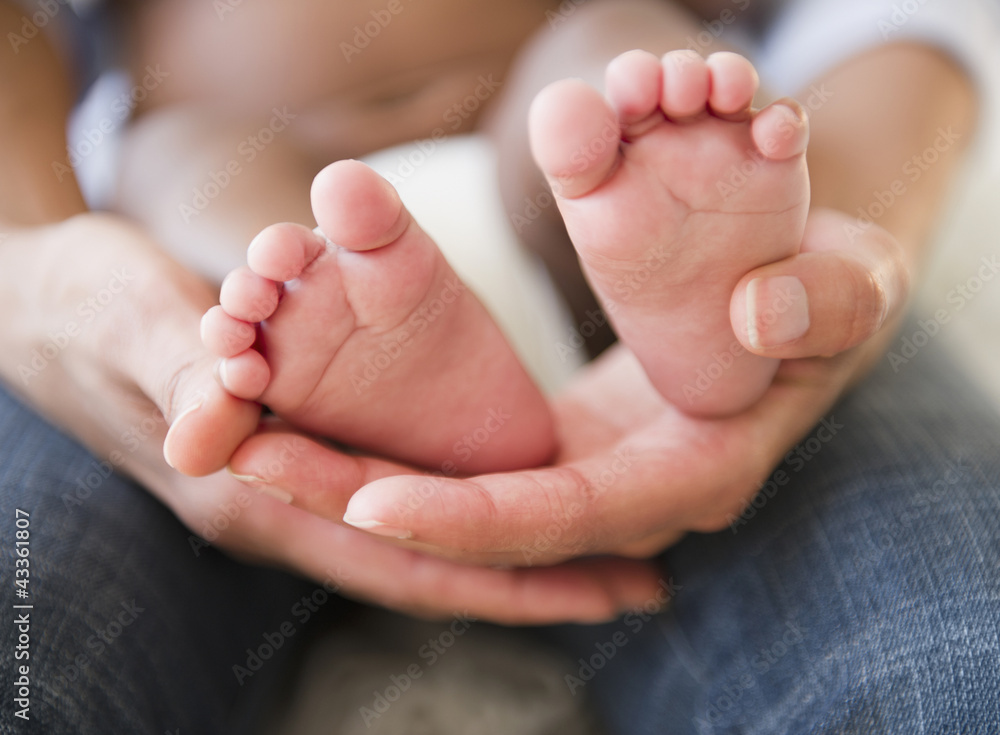 Close up of African American mother holding baby's feet Close up of African American mother holding baby's feet