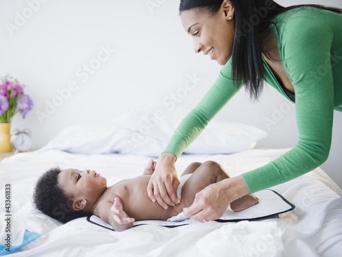 African American mother changing son's diaper photo