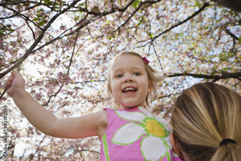 Mother lifting daughter under spring flowers Mother lifting daughter under spring flowers