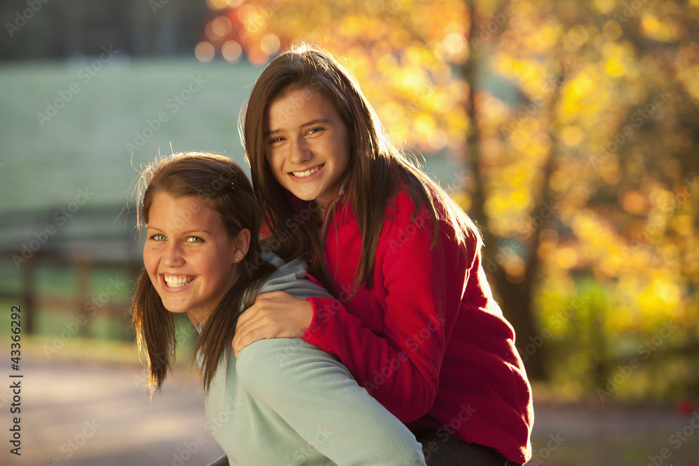 Caucasian girl carrying friend on her back Caucasian girl carrying friend on her back