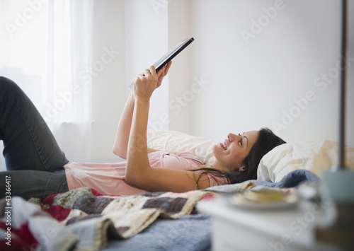 Brazilian woman using digital tablet in bed