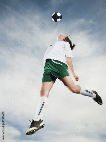 Caucasian teenager heading soccer ball in mid-air photo