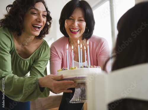Grandmother and mother giving birthday cake to daughter photo
