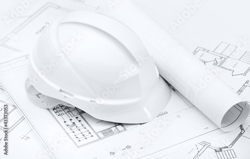 White hard hat on working or engineering drawings