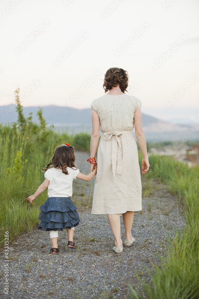 Caucasian mother and daughter walking on path Caucasian mother and daughter walking on path