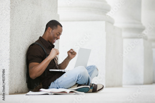 Black college student using laptop outdoors photo