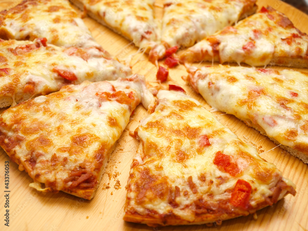 Sliced fresh pizza with red pepper on wooden board Sliced fresh pizza with red pepper on wooden board