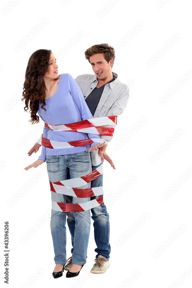 Couple being forcibly held together by caution tape Couple being forcibly held together by caution tape
