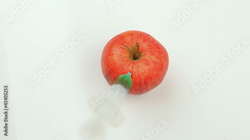 Syringe injecting a toxic product in an apple