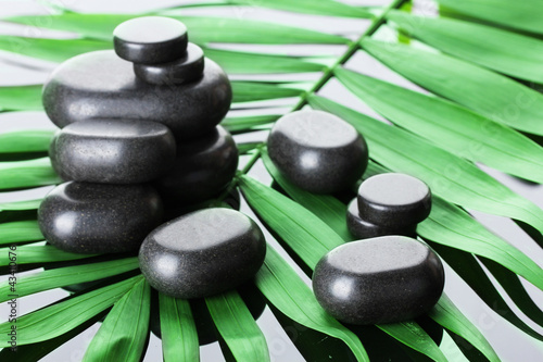 Spa stones on green palm leaf on grey background