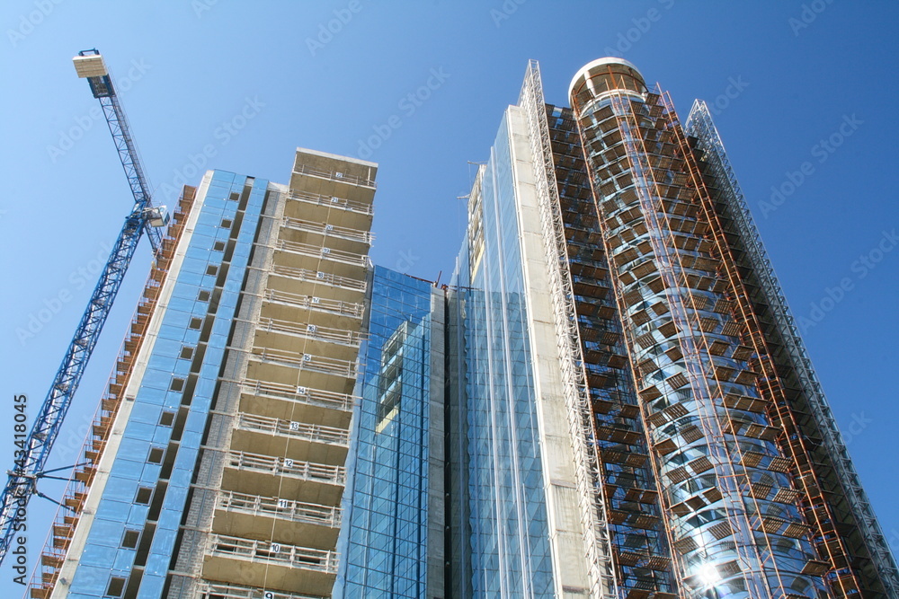 Fototapeta premium Modern high-rise building under construction and a crane.
