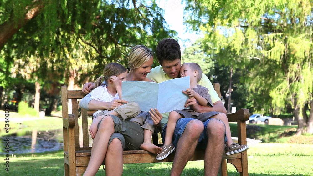 Family reading a book while sitting on a bench Family reading a book while sitting on a bench