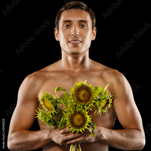 Sexy young muscular man with a bouquet of flowers in his hands