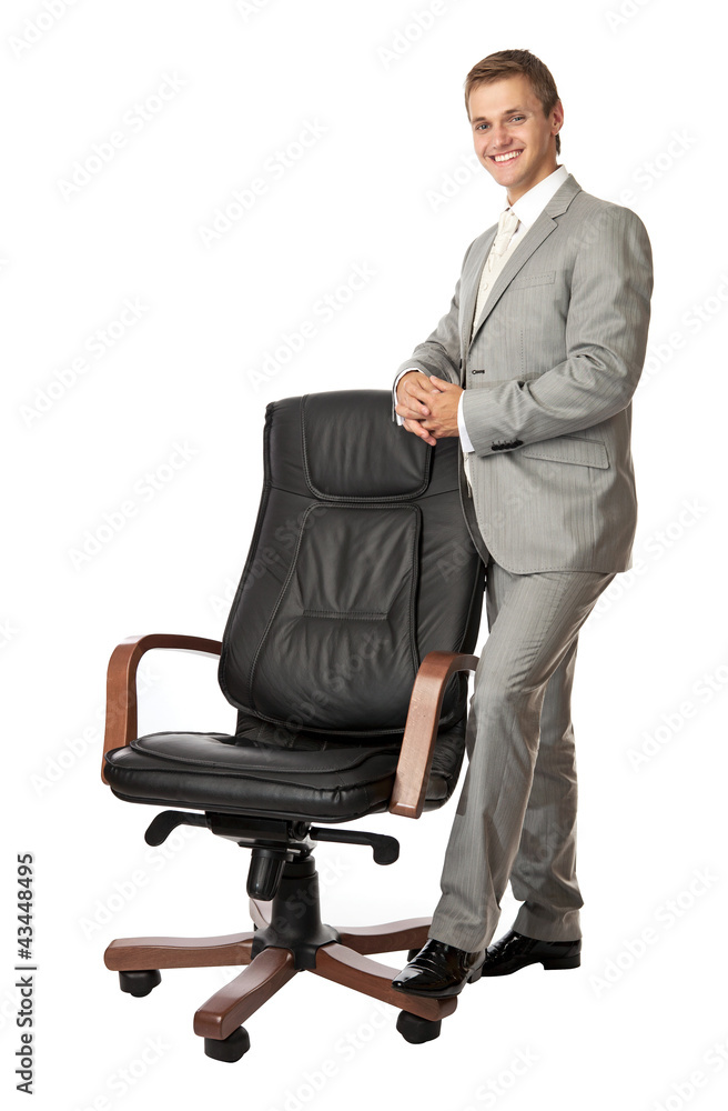 Handsome young man standing next to an armchair Handsome young man standing next to an armchair